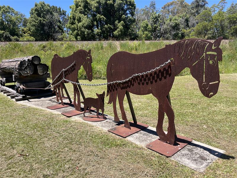 Escultura de silhuetas de cavalos de metal rebocando madeira no bonde