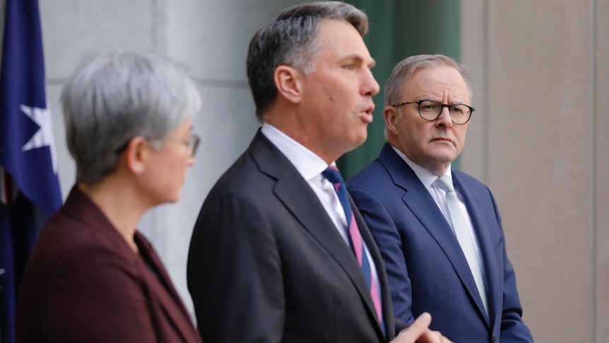 Wong, Marles and Albanese stand at lecterns in a courtyard speaking.