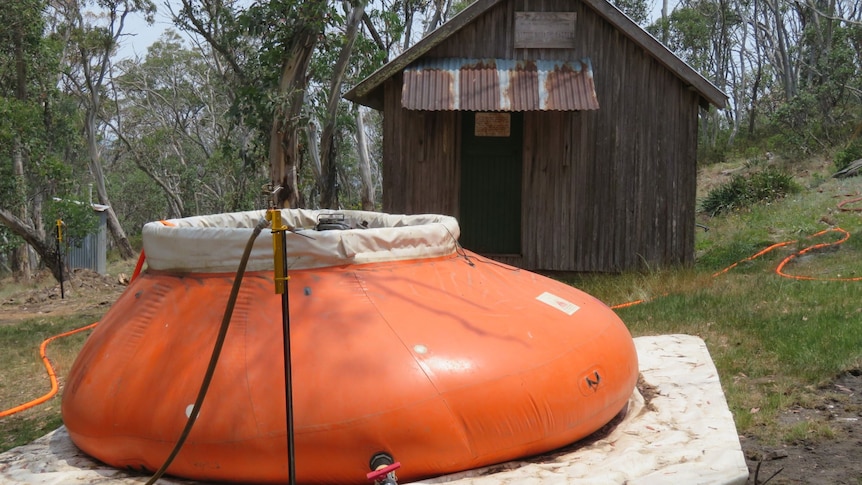 An orange inflatable pool set up outside an old shack.
