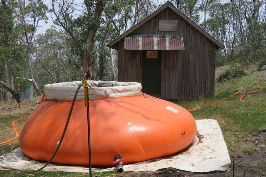An orange inflatable pool set up outside an old shack.