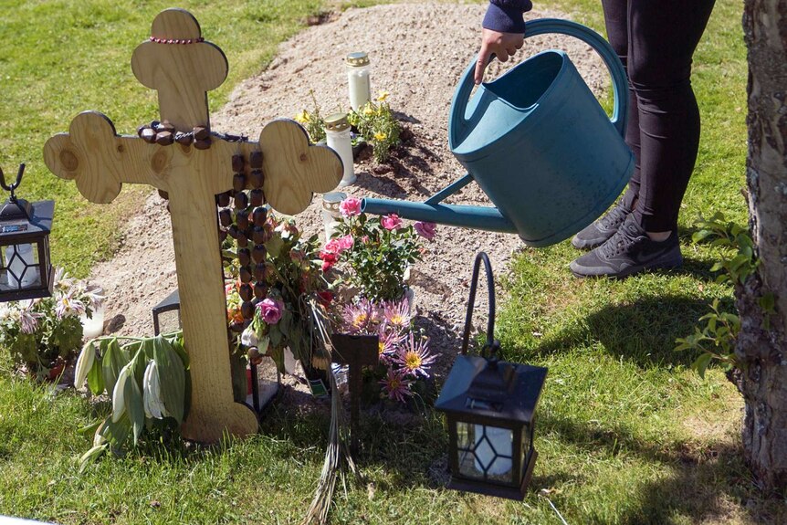 Mirrey Gourie waters the flowers on her father's grave.
