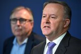Anthony Albanese and Michael Lavarch (blurred in the background) speak at a media conference.