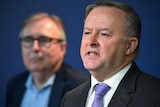 Anthony Albanese and Michael Lavarch (blurred in the background) speak at a media conference.