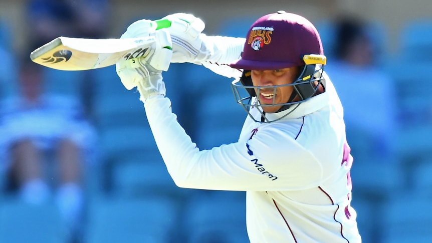 Usman Khawaja finishes playing a shot in Queensland Bulls Sheffield Shield gear.