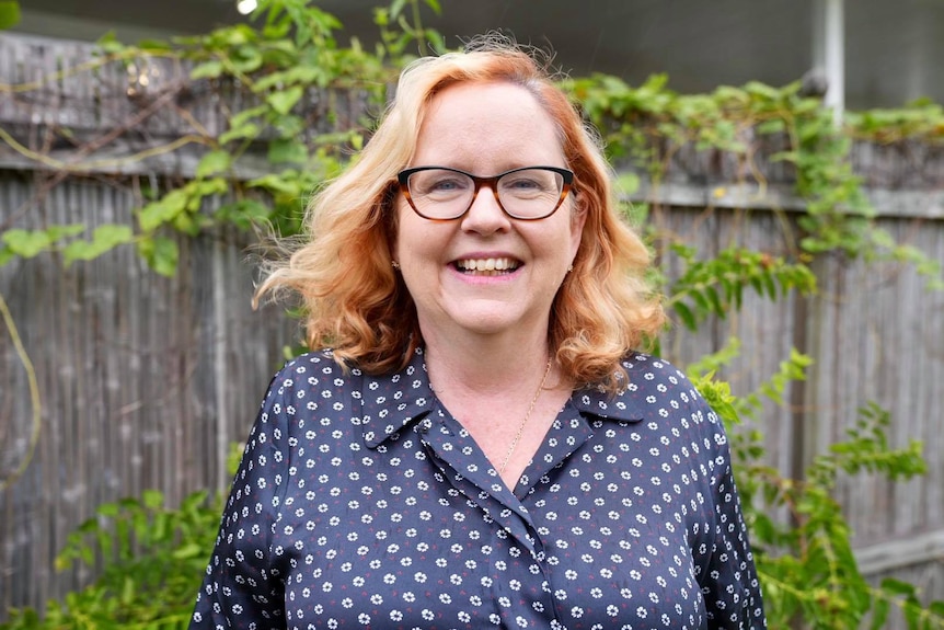 A woman stands in garden smiling.