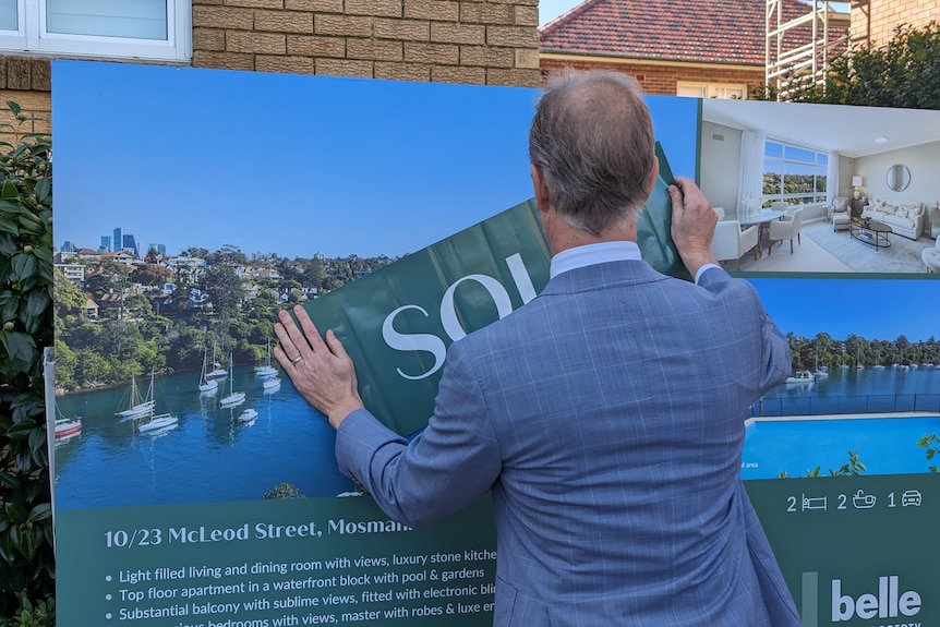 Real estate agent puts up a sold sticker after this Mosman apartment sold at auction.