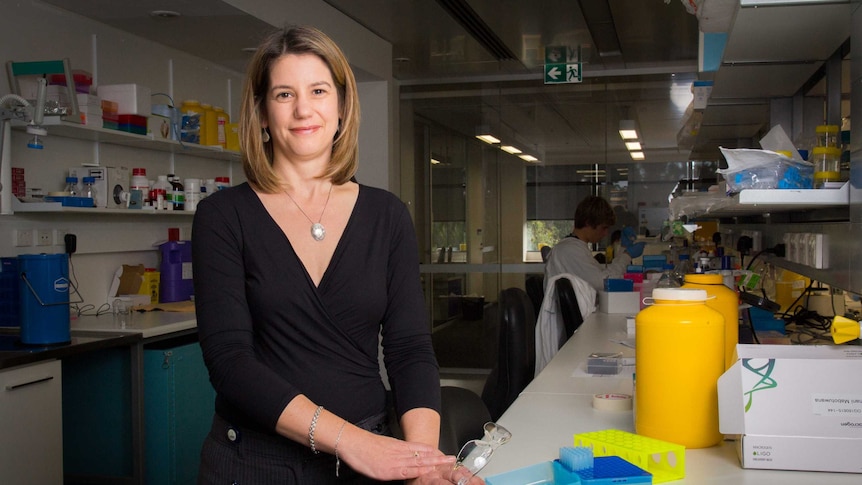 Dr Coralie English stands next to a laboratory bench.