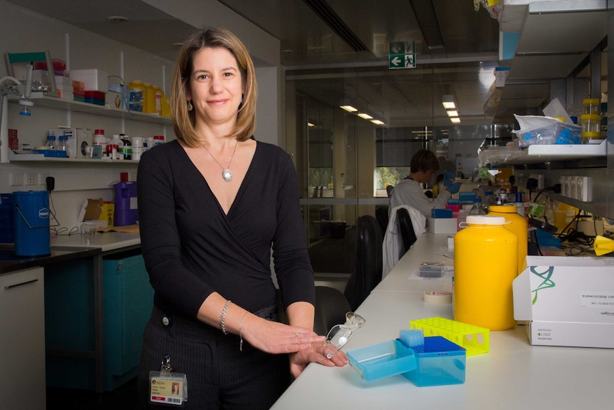 Dr Coralie English stands next to a laboratory bench.