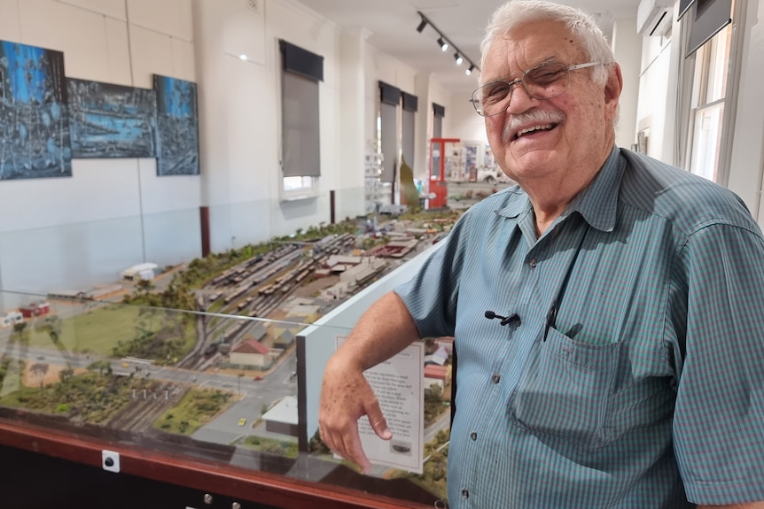 Morrey Russell standing in front of his model town, smiling.