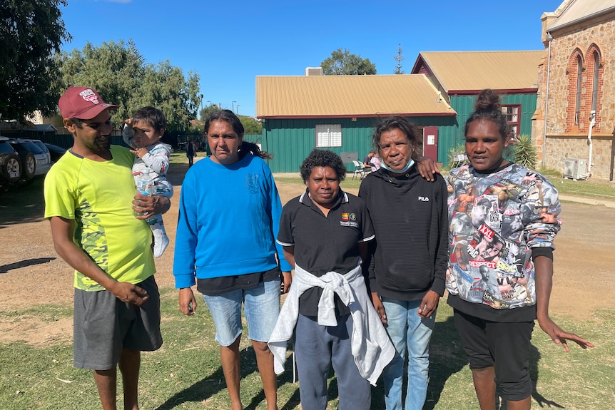 One Aboriginal man, left and four Aboriginal woman. The man is holding a baby. 