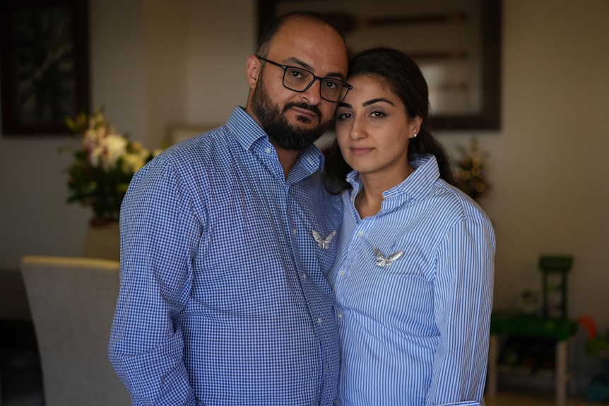 A man and woman stand with their heads touching