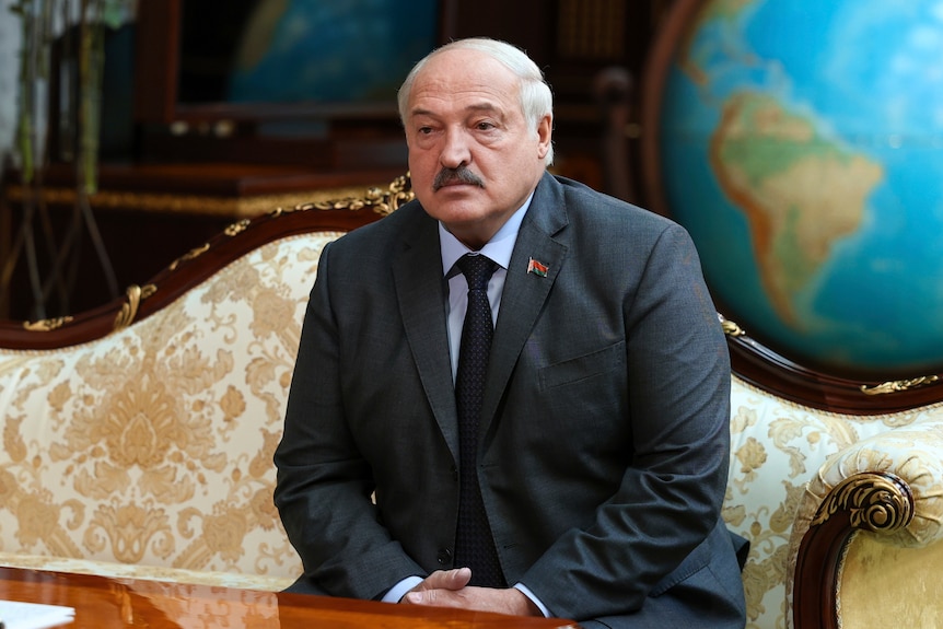 Alexander Lukashenko in a suit sitting down in a suit and tie