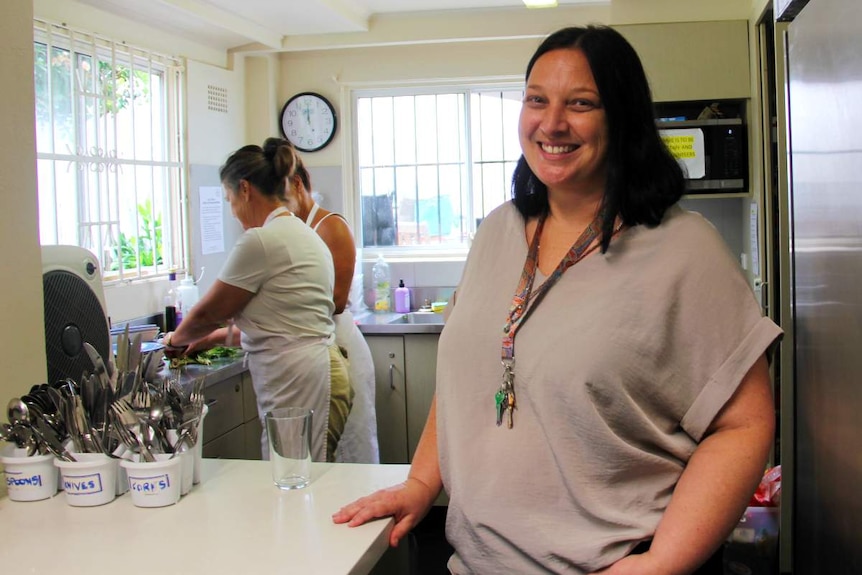 A woman smiles while standing in a kitchen