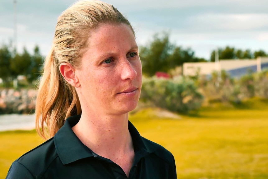 Simone stands in a field with yellow grass in the background.