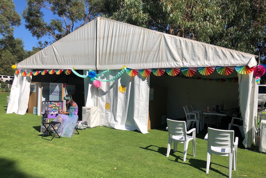 A white tent in Kings Park with a female face painter sitting out the front