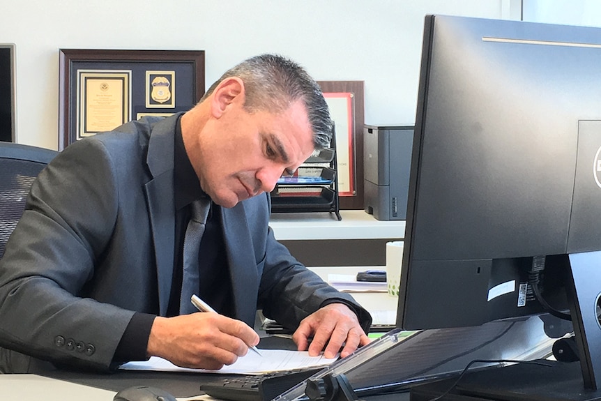 New ASADA boss David Sharpe looks down and writes in his office.