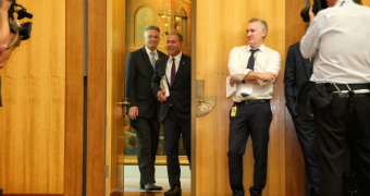 Josh Frydenberg walks into a room full of reporters holding a budget folder.