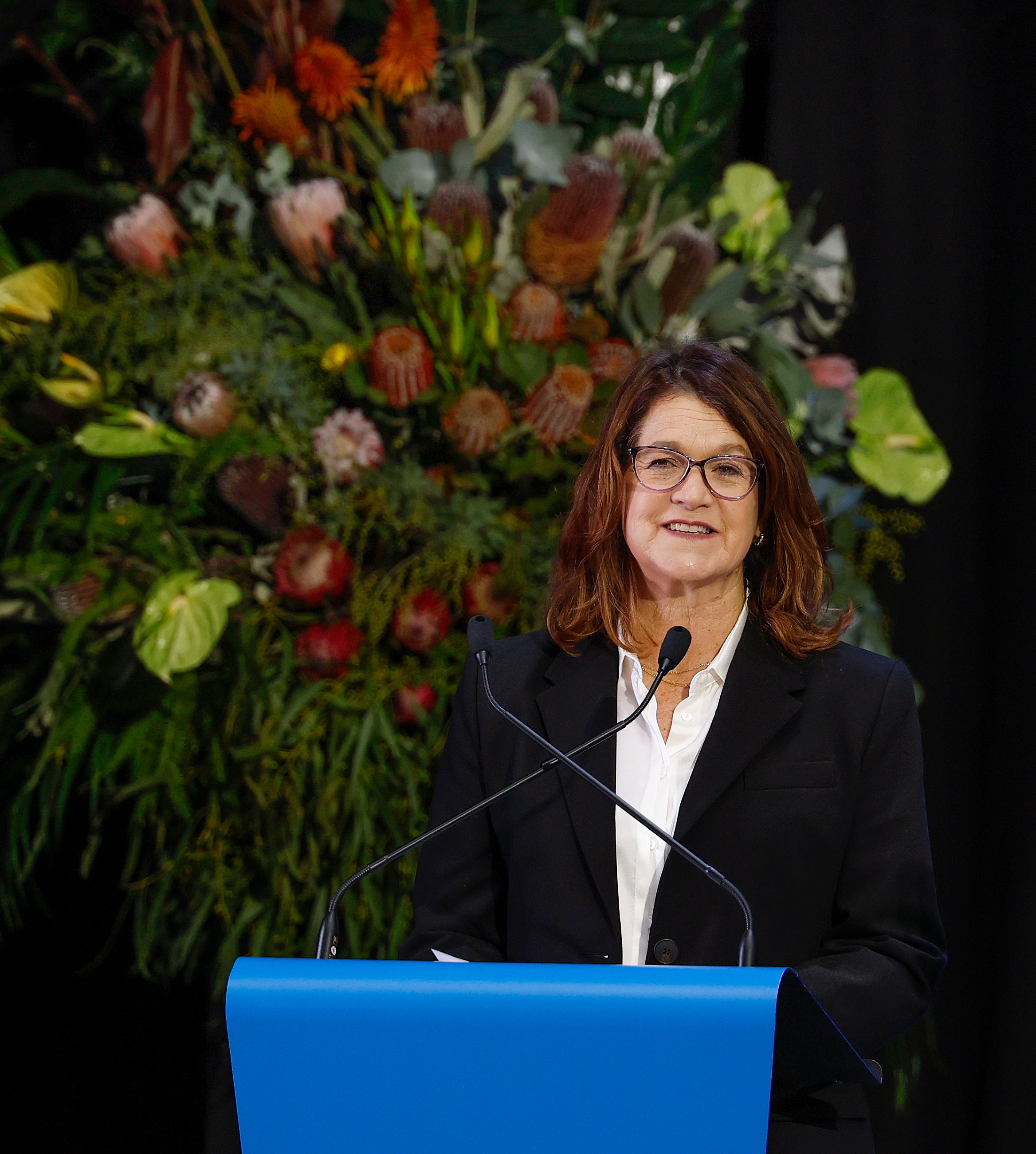 Neale Daniher's wife Jan smiles on stage as she speaks at his state funeral at the MCG.