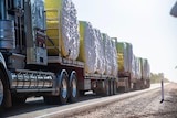 A truck carrying massive bails of cotton passes on a highway.