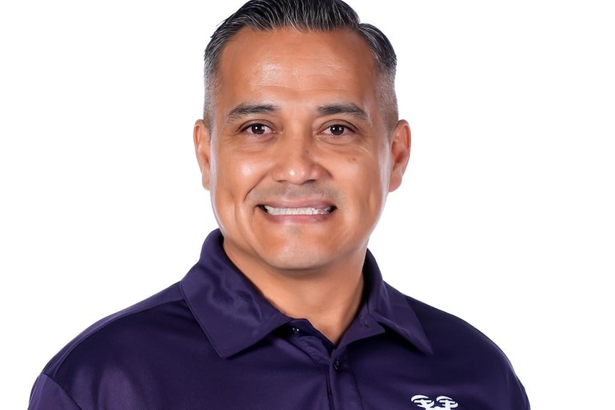 A Guam man smiling in a dark purple collared tee shirt