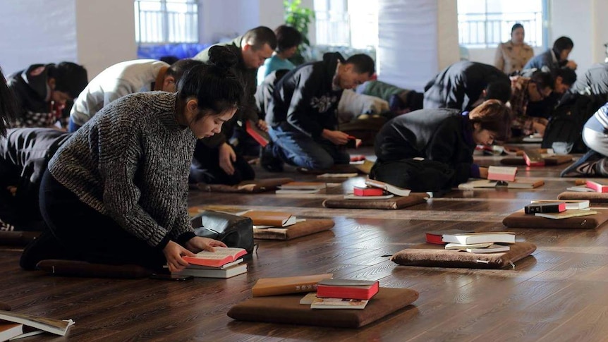 Worshippers at the Early Rain Covenant Church in Chengdu pray on the floor, bowing with bibles and pillows.