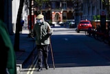 An elderly man with two walking sticks in a face mask