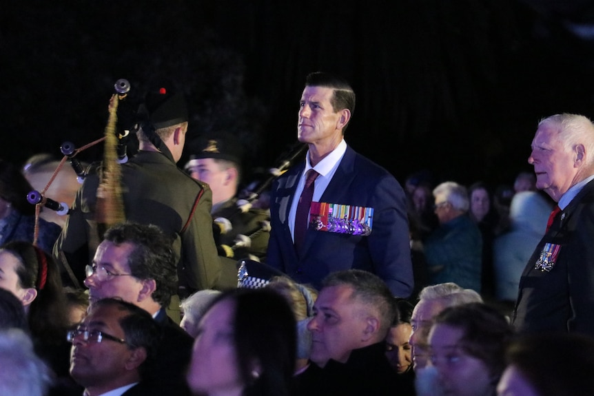 A man wearing many medals stands out from the crowd.