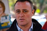 Tim Wilson talks to the media in front of a campaign sign for his challenger Zoe Daniel