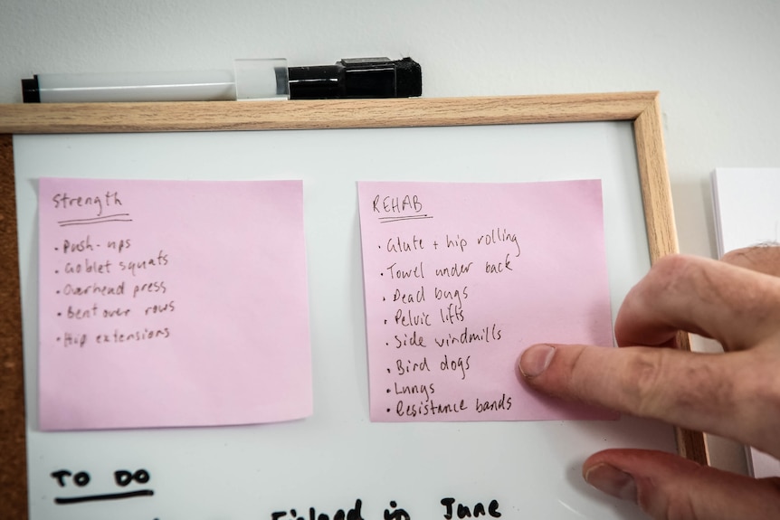 Two pink post-it notes are stuck on a whiteboard. One lists exercises under the word "strength", the other "rehab".