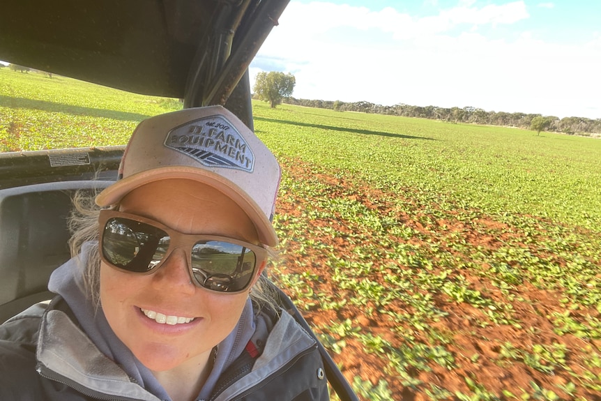 Young farmer smiles from buggy surrounded by green fields