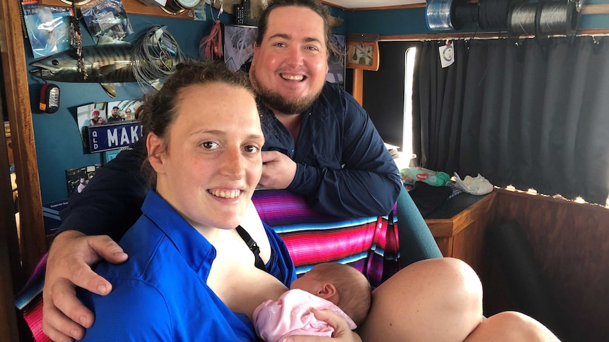 A mother breastfeeds her newborn baby in the wheelhouse of a fishing boat, as Dad stands close by