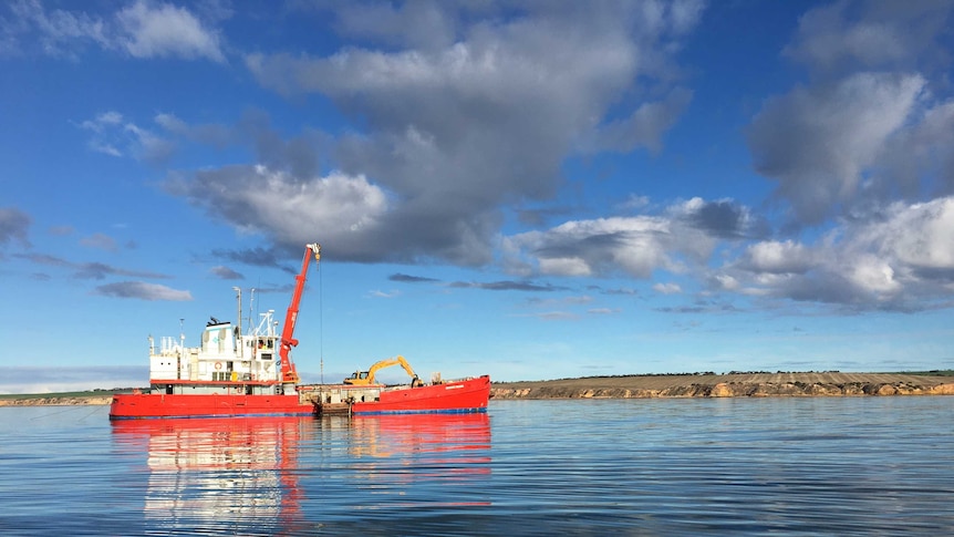 A construction vessel anchored off the coast of Ardrossan is sinking limestone blocks into the ocean.