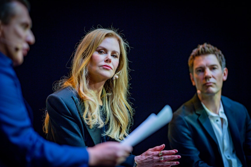 Nicole Kidman and Per Saari in focus, Peter Overton slightly out of focus, the three sitting on stage against a black background