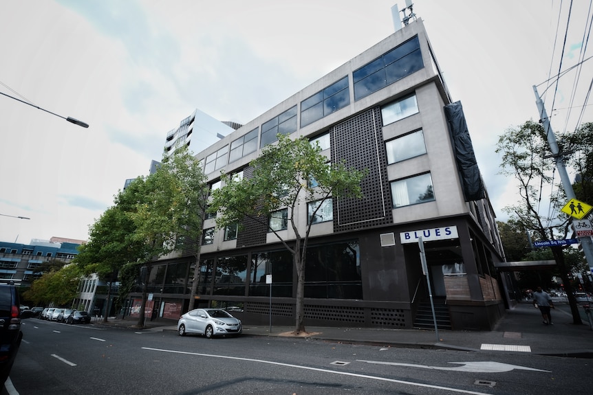 The exterior of a multi-floor building, with a road in front. 