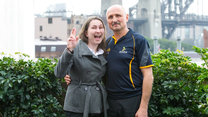 Elena Galiabovitch smiles and her dad Vlad strikes a serious pose in front of the Sydney Harbour Bridge.