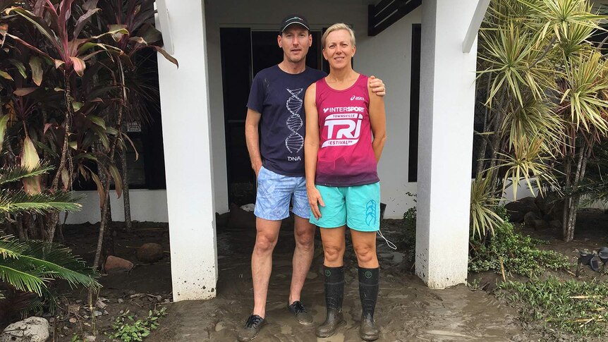 Clayton and Carmel Linning stands outside their muddy, flood-damaged house.