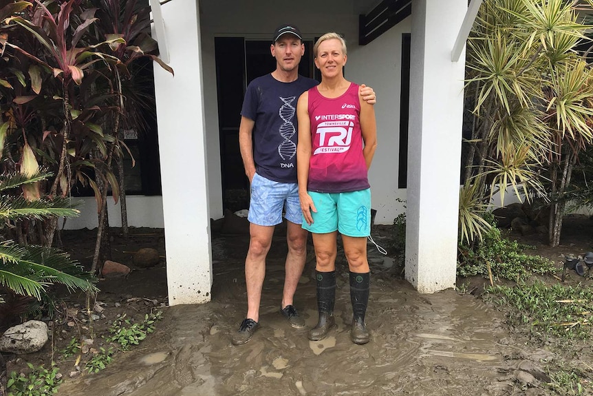 Clayton and Carmel Linning stands outside their muddy, flood-damaged house.