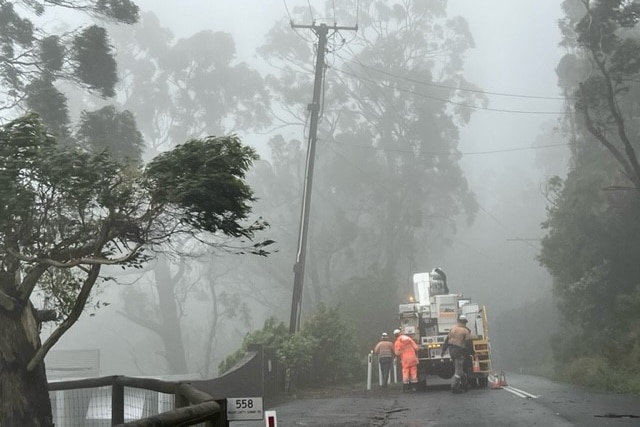 A team of repairman at work on powerlines in the midst of a ferocious storm.