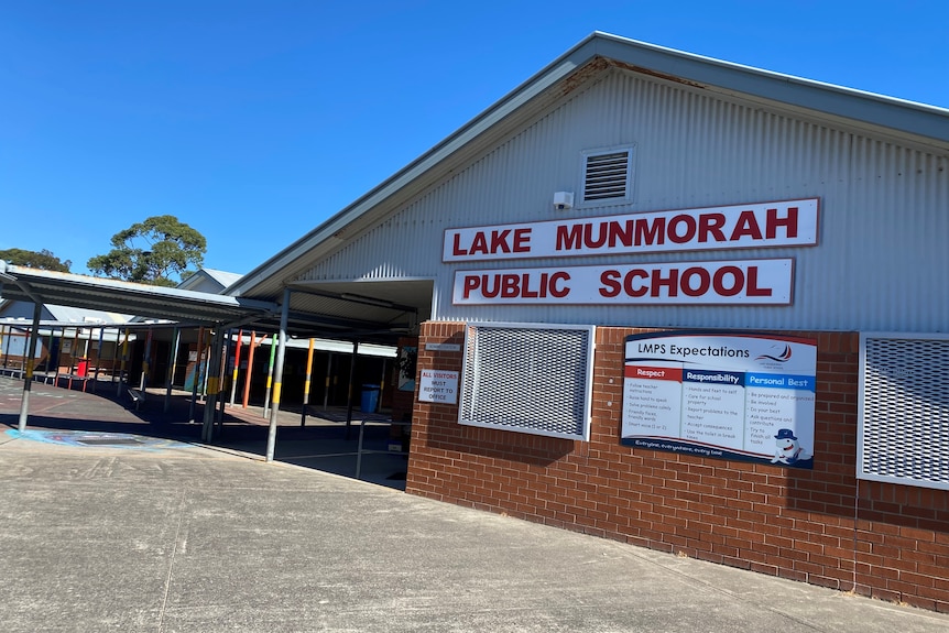 the front entrance to a school with a sign on the wall saying Lake Munmorah Public School 