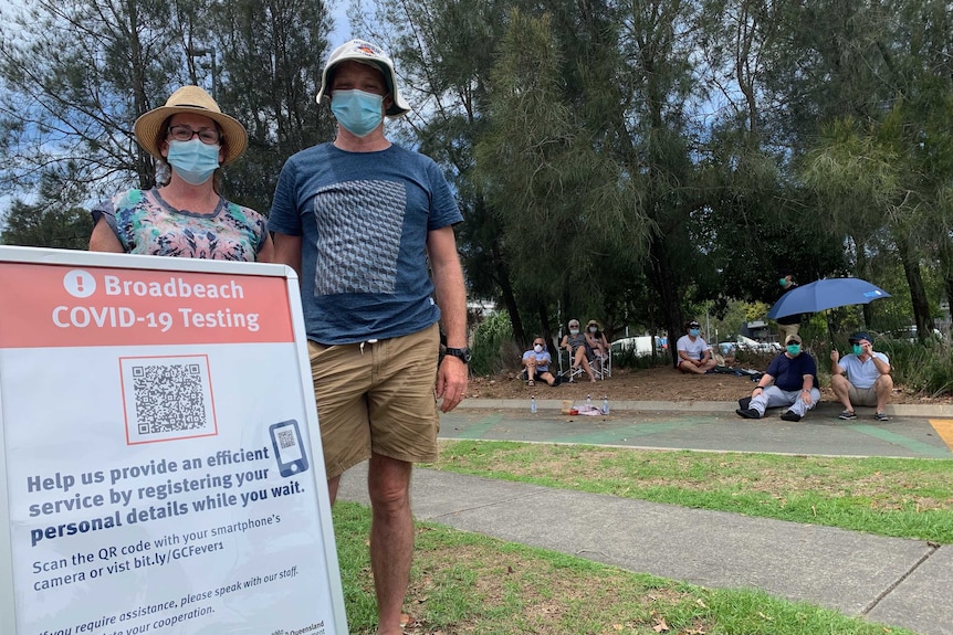 A long line of people wearing face masks outside a brick building