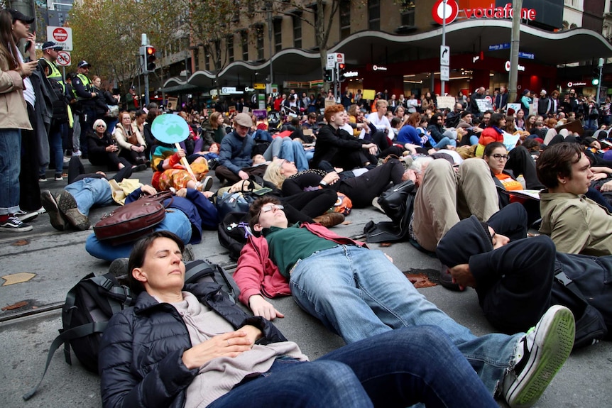 People lie on the ground in a mock die-in at a climate rally.