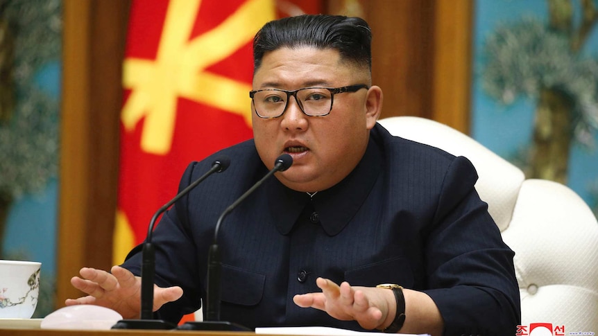 North Korean leader Kim Jong-un speaks in front of North Korean flags.