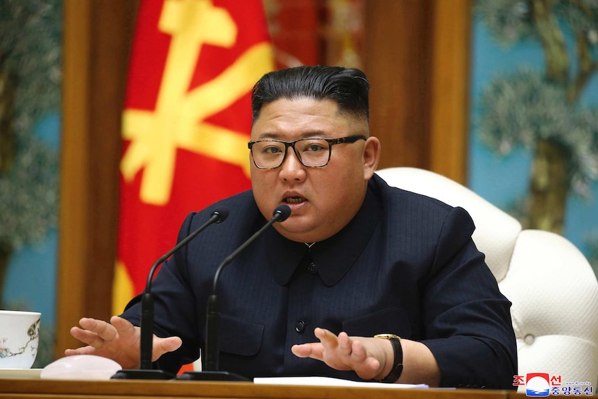 North Korean leader Kim Jong Un speaks in front of North Korean flags.