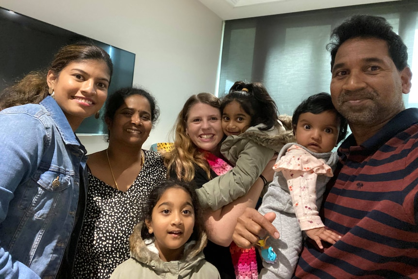 Selfie of a group of adults and children in a hospital corridor.