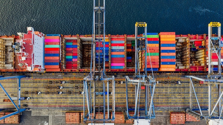 An aerial shot of a large container ship at a dock.