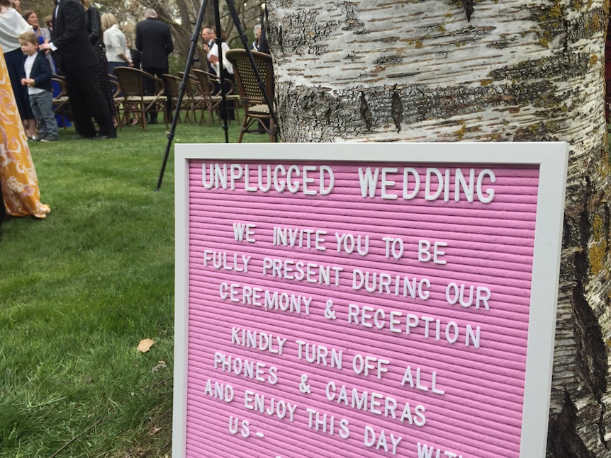 A sign requesting guests to turn off mobile phones and cameras during an unplugged wedding.