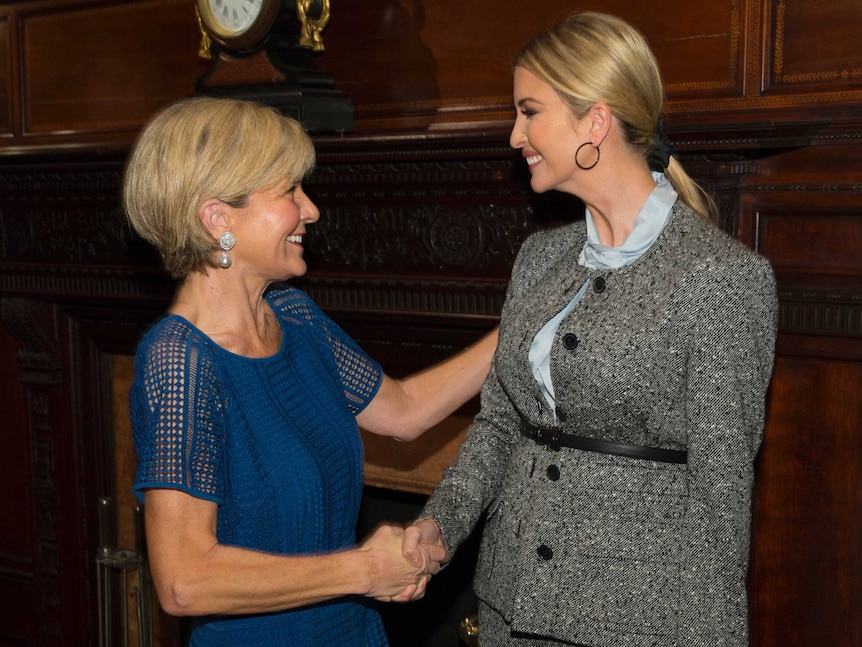 Two women professionally dressed shake hands with big smiles on their faces