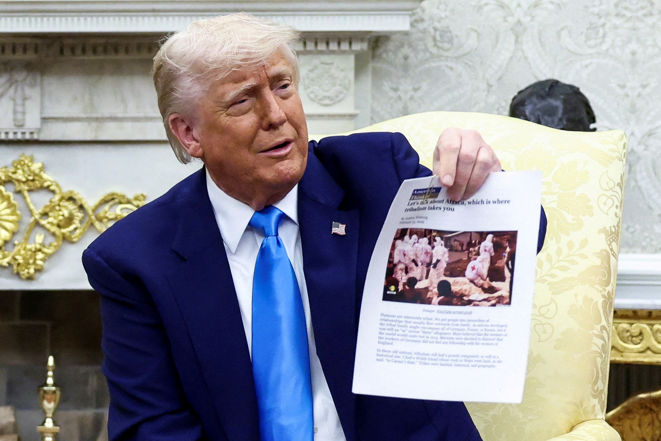 Donald Trump holds up a print-out of a news article.