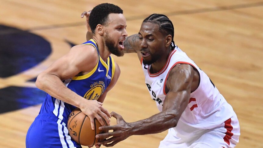 Stephen Curry holds the ball at hip level as Kawhi Leonard uses his left hand to try to steal the ball.