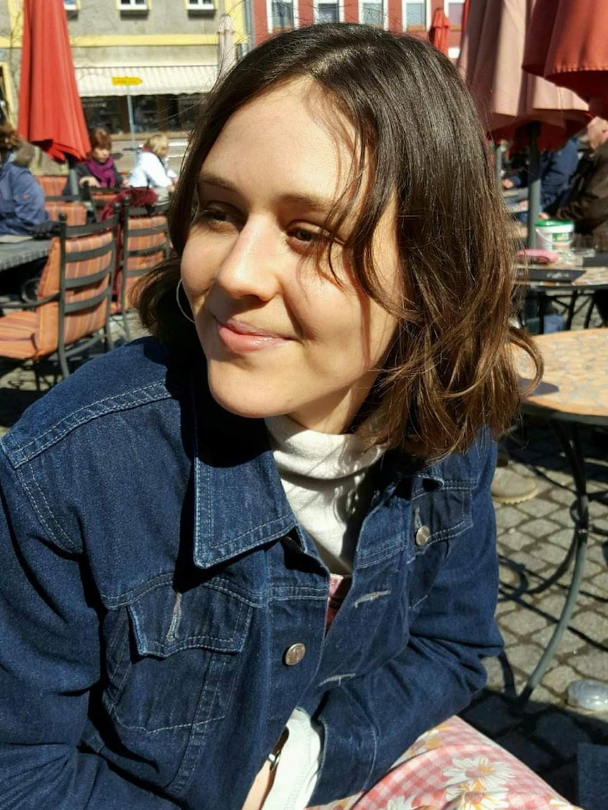 A woman sits at an outdoor table.